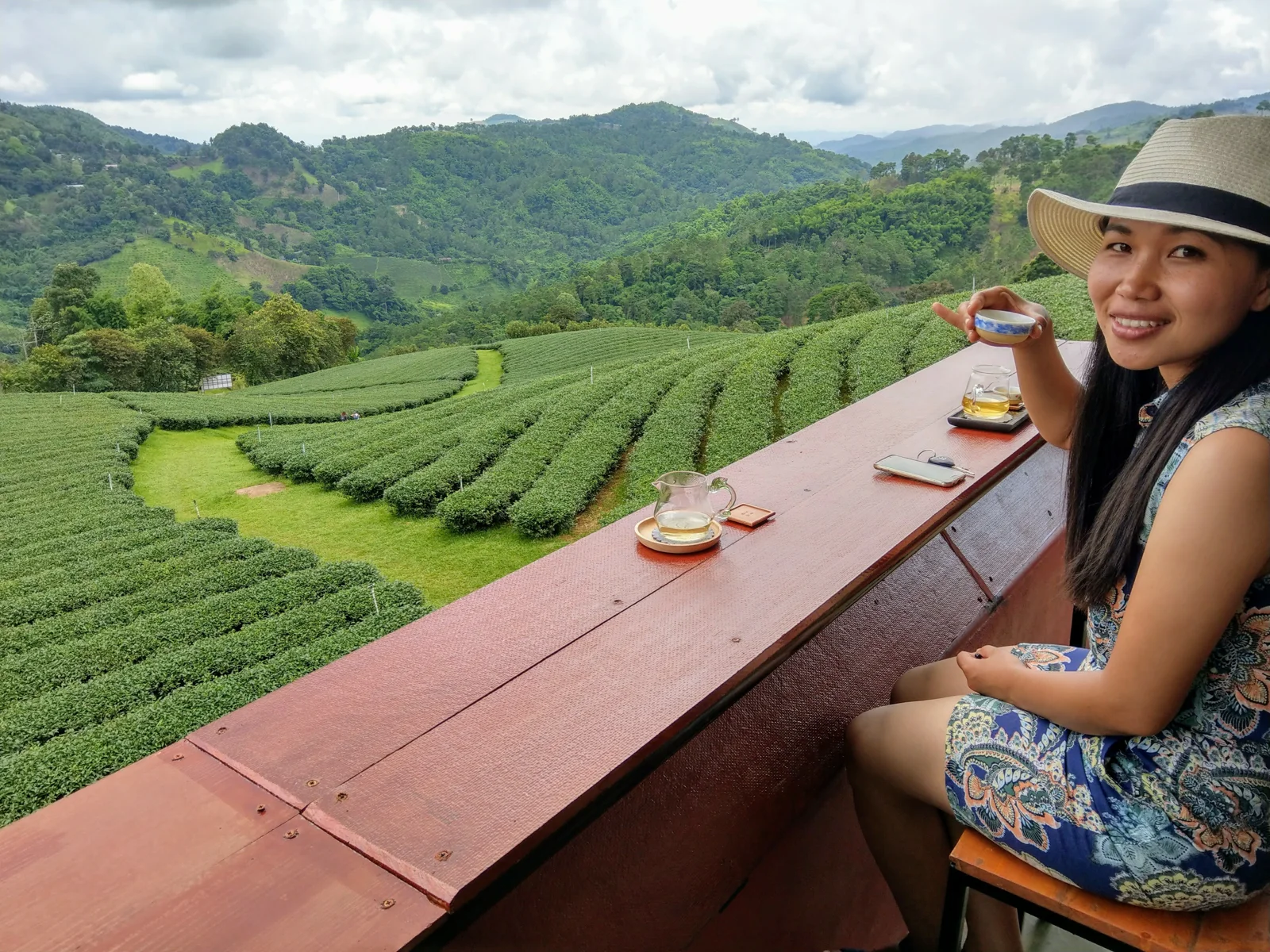 A woman beside a view of green fields and hills