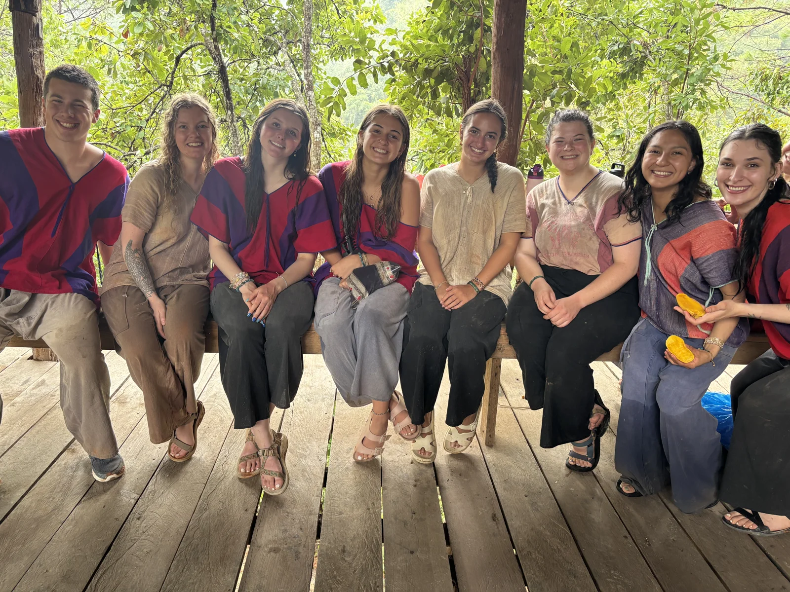Participants and local community members sitting together on a wooden platform