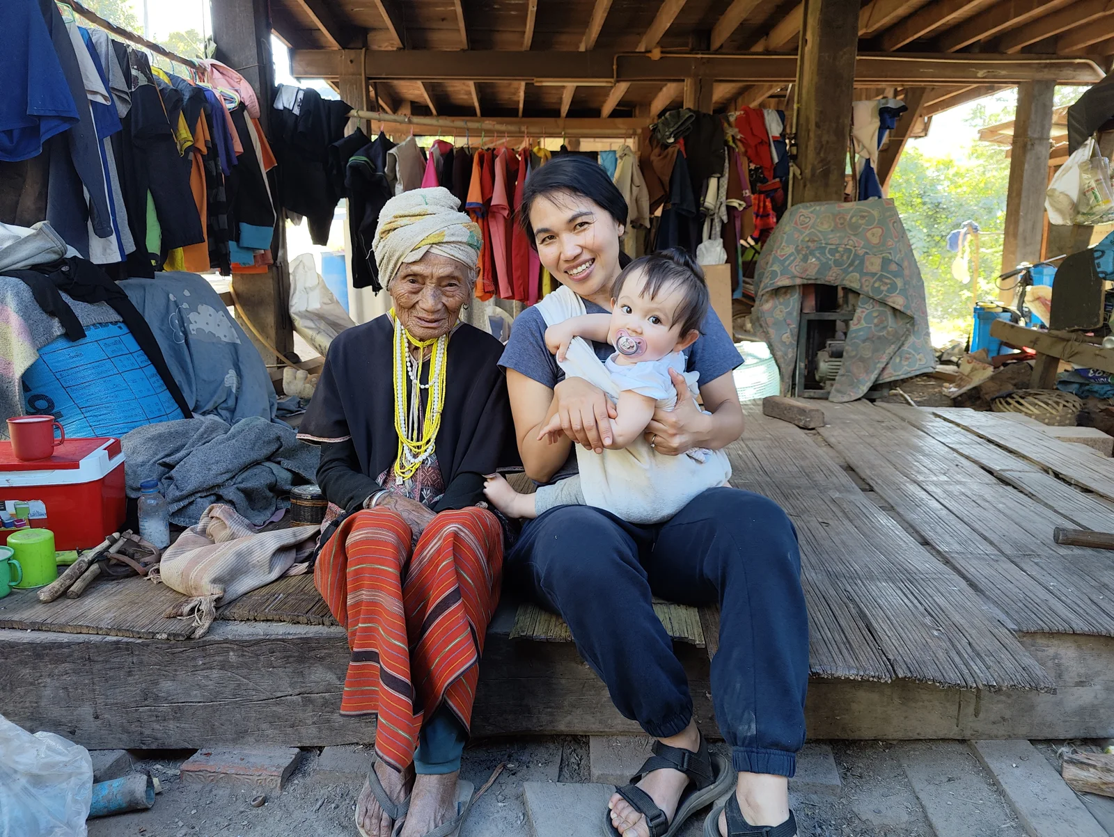 A community elder and a woman holding a young child, seated together in a village home