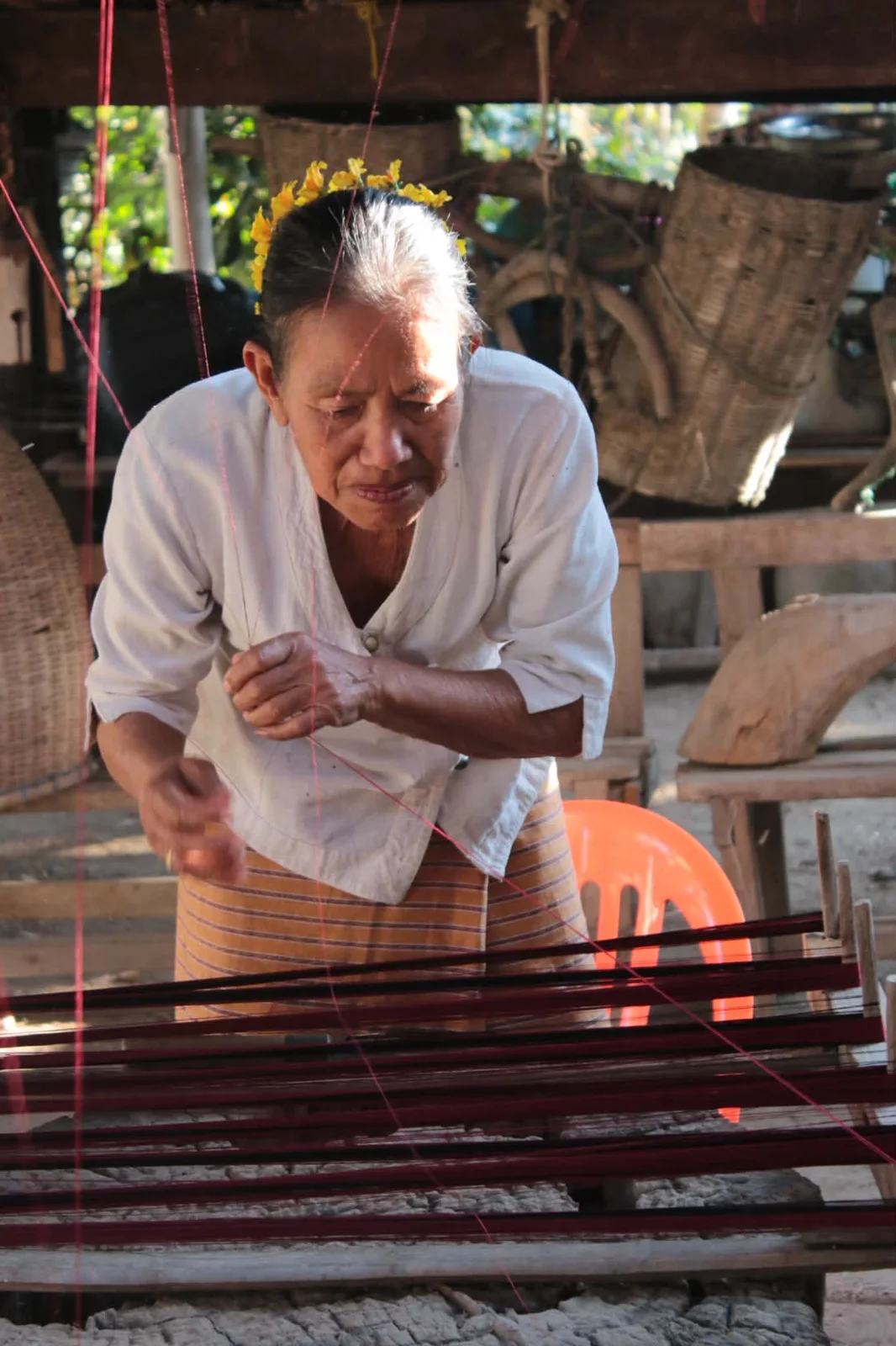A craftsperson working with threads at a loom