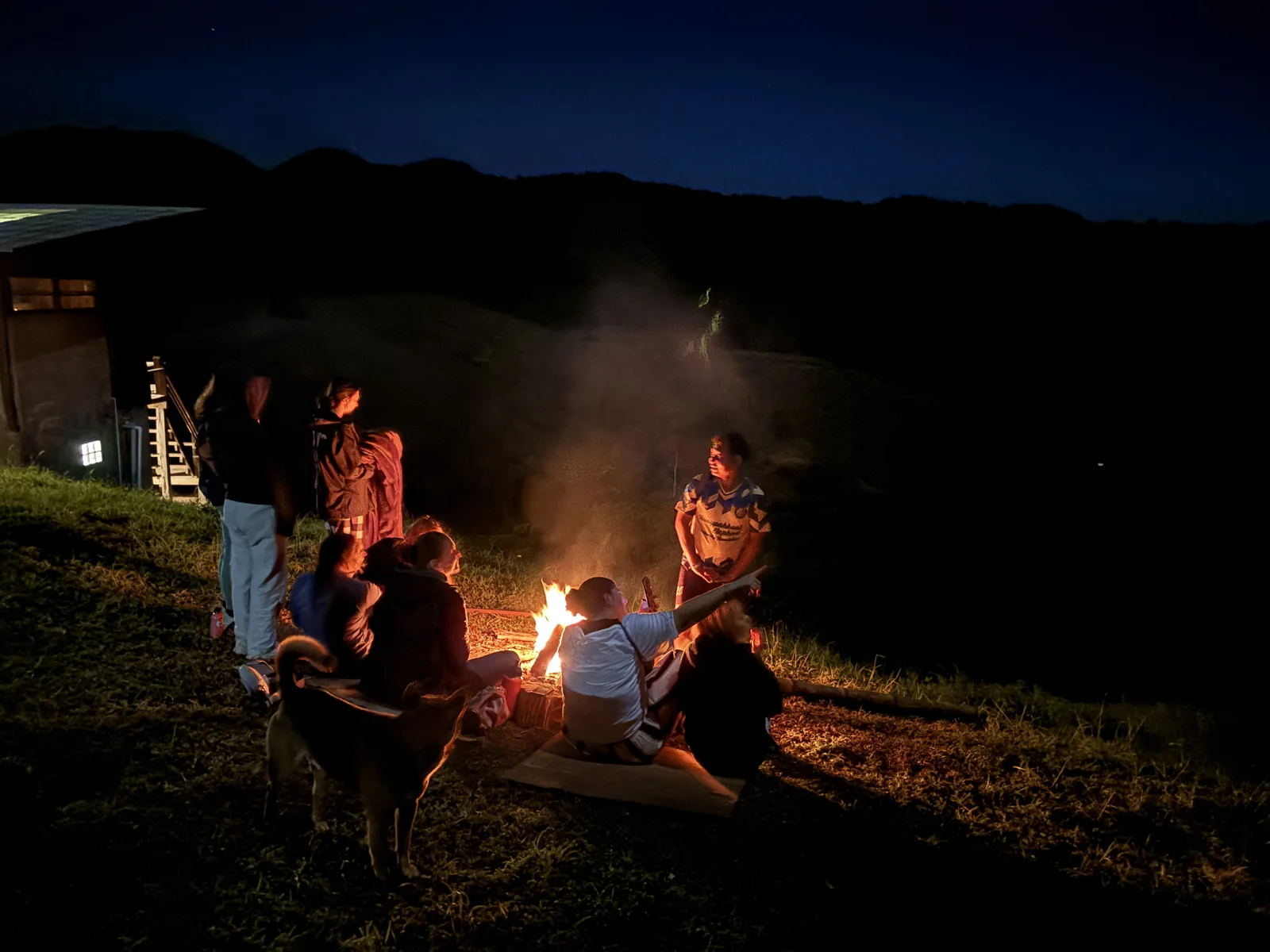 People sitting together around an outdoor fire at dusk