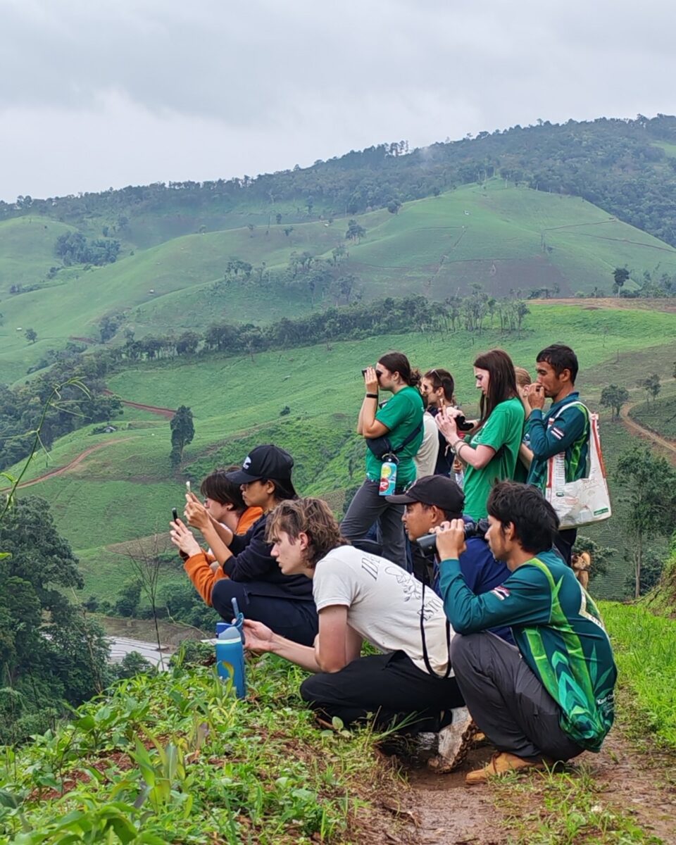 Home Students observing the landscape with binoculars in the green hills of Northern Thailand